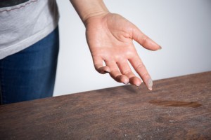 Close-up of dust on woman finger taken from wooden table